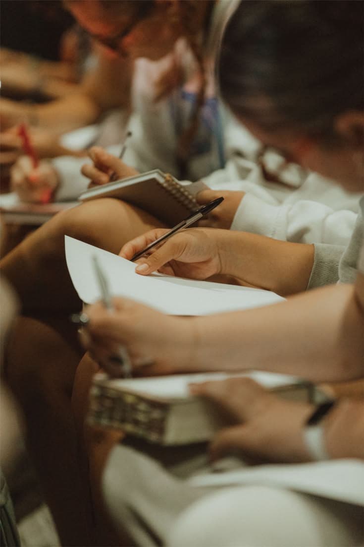 Mãos escrevendo em cadernos e folhas durante o encontro